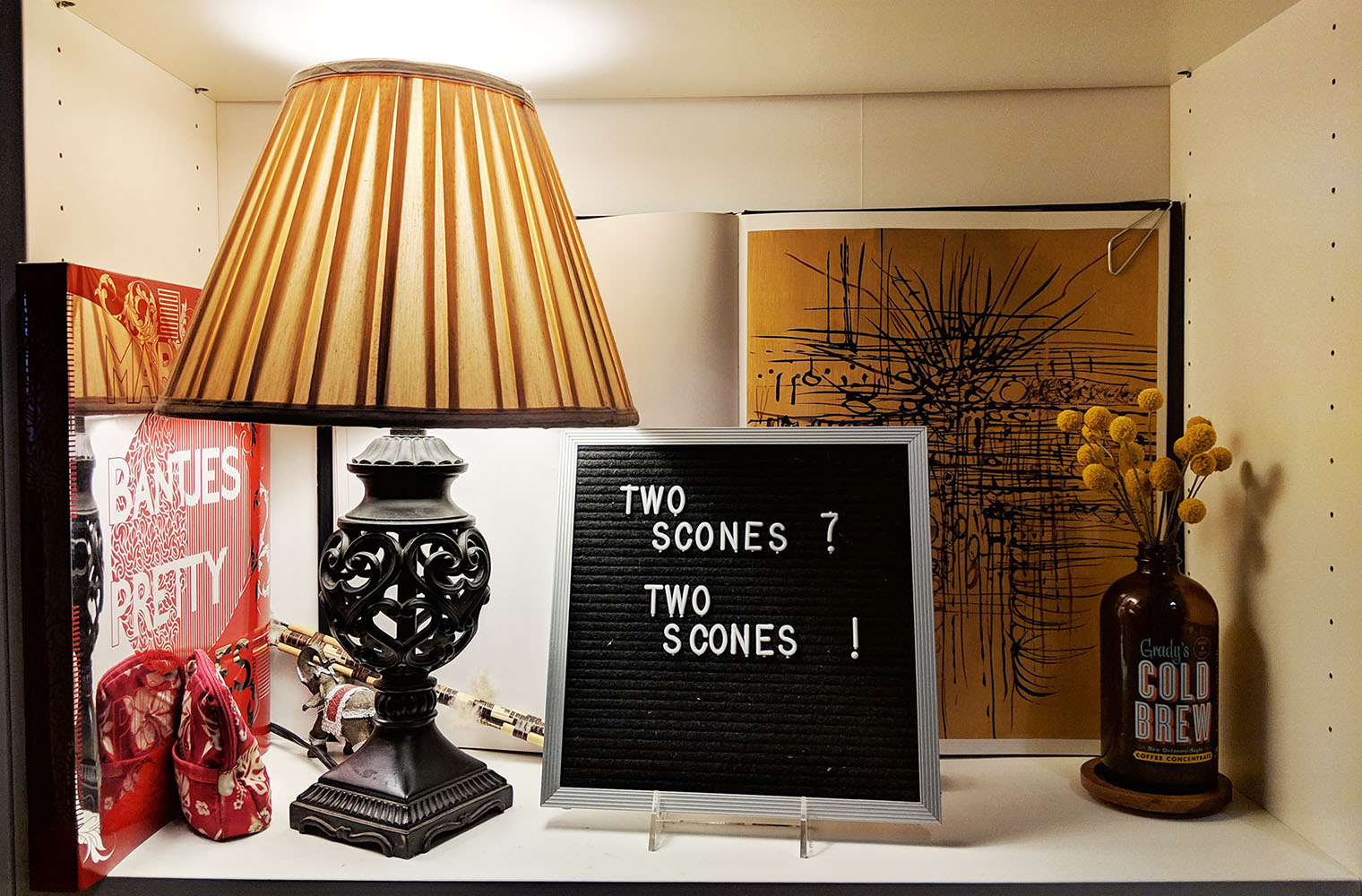 Lamp and 'Two scones?' sign on shelf